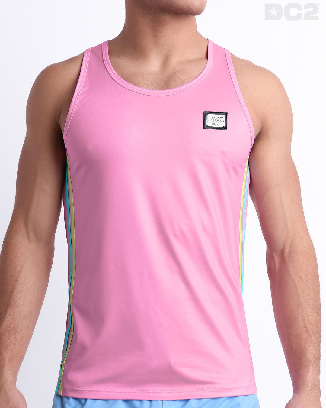 Male model wearing men’s PADAM PINK men’s Summer Tank Top in a pink color with stylish pastel yellow and aqua colored stripes. This high-quality shirt is by DC2, a men’s beachwear brand from Miami.