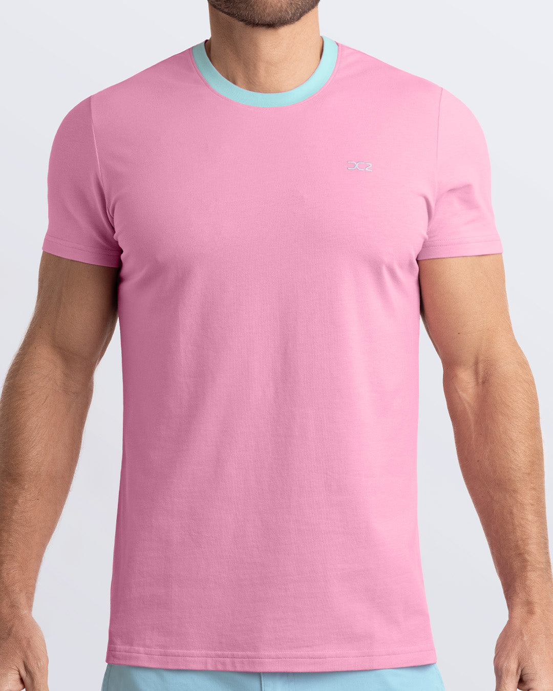 Frontal view of a male model wearing a solid light pink Pima cotton t-shirt with a light blue collar, crafted for stylish casual wear and beachwear by DC2 Miami. Premium quality men's streetwear t-shirt, perfect fit for summer fashion.