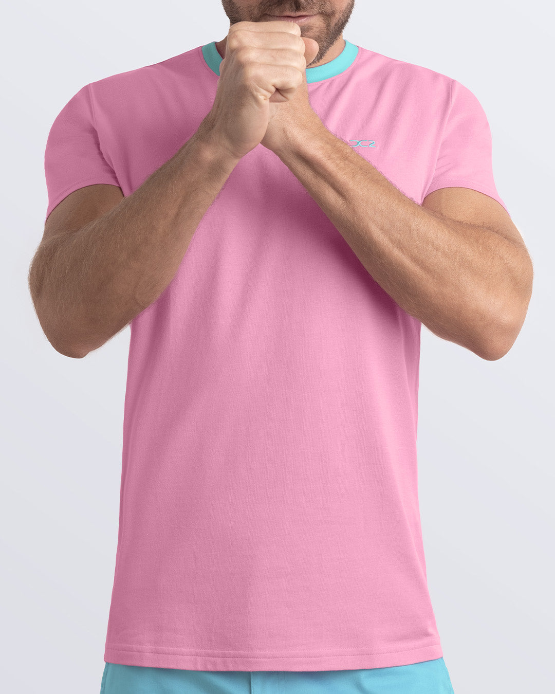 A model wearing the PADAM PINK, a light pink Pima cotton t-shirt with a light aqua collar, showcasing the breathable, lightweight fabric ideal for summer beachwear and street style. Part of the DC2 Miami men's casual collection, featuring a perfect fit for active wear.