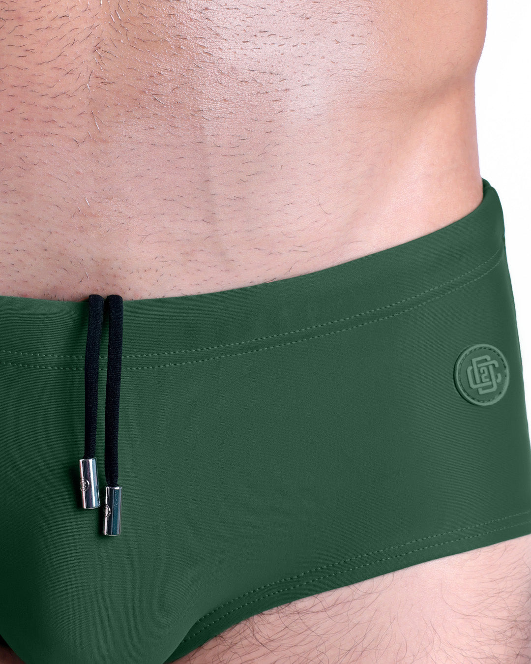 Close-up view of the PALM GREEN men’s drawstring briefs showing black cord with custom branded metallic silver cord ends, and matching custom eyelet trims in silver.