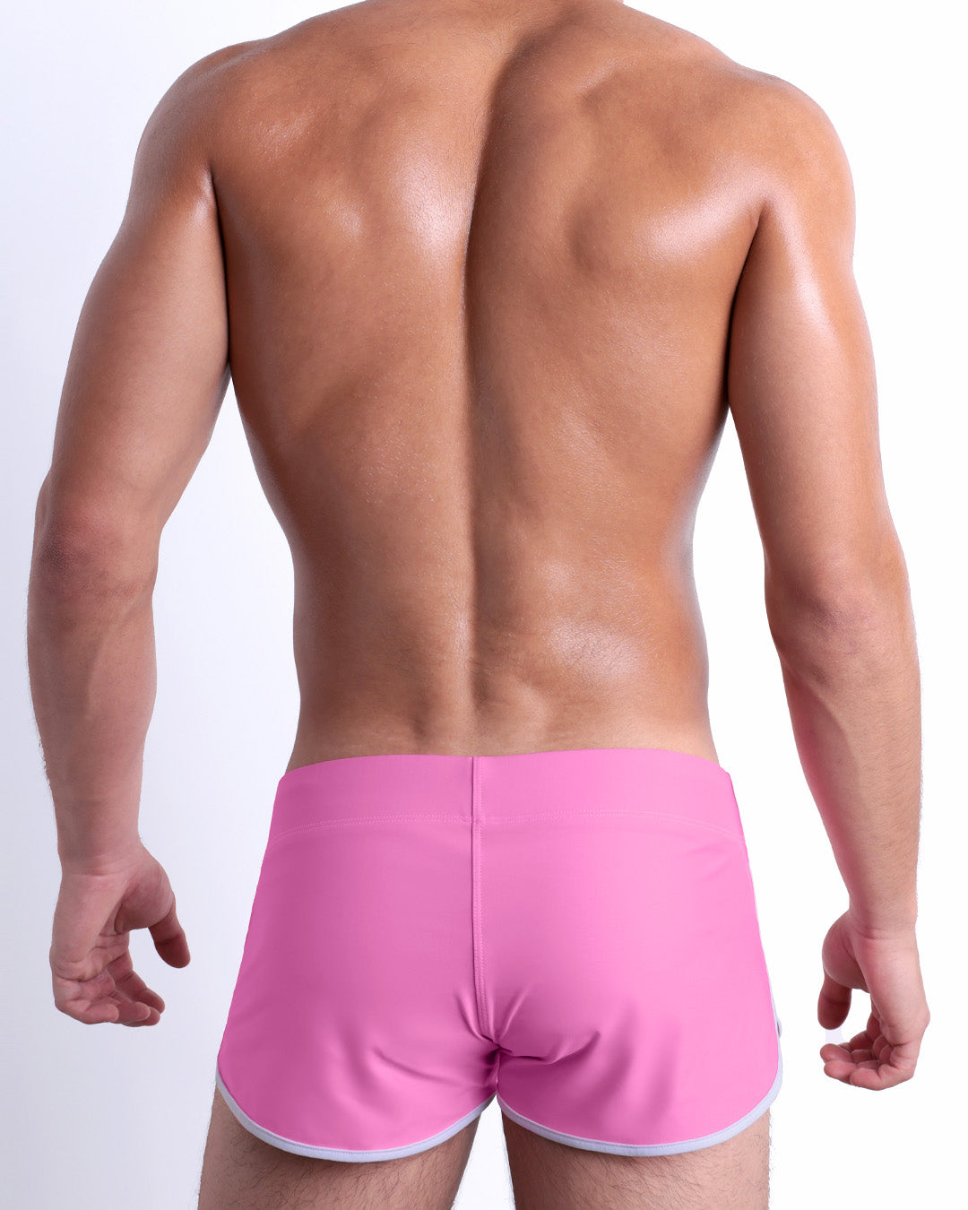 Back view of a male model wearing the PINKTYQUE beach Swim Shorts for men by DC2 Miami in a solid vibrant pink color.