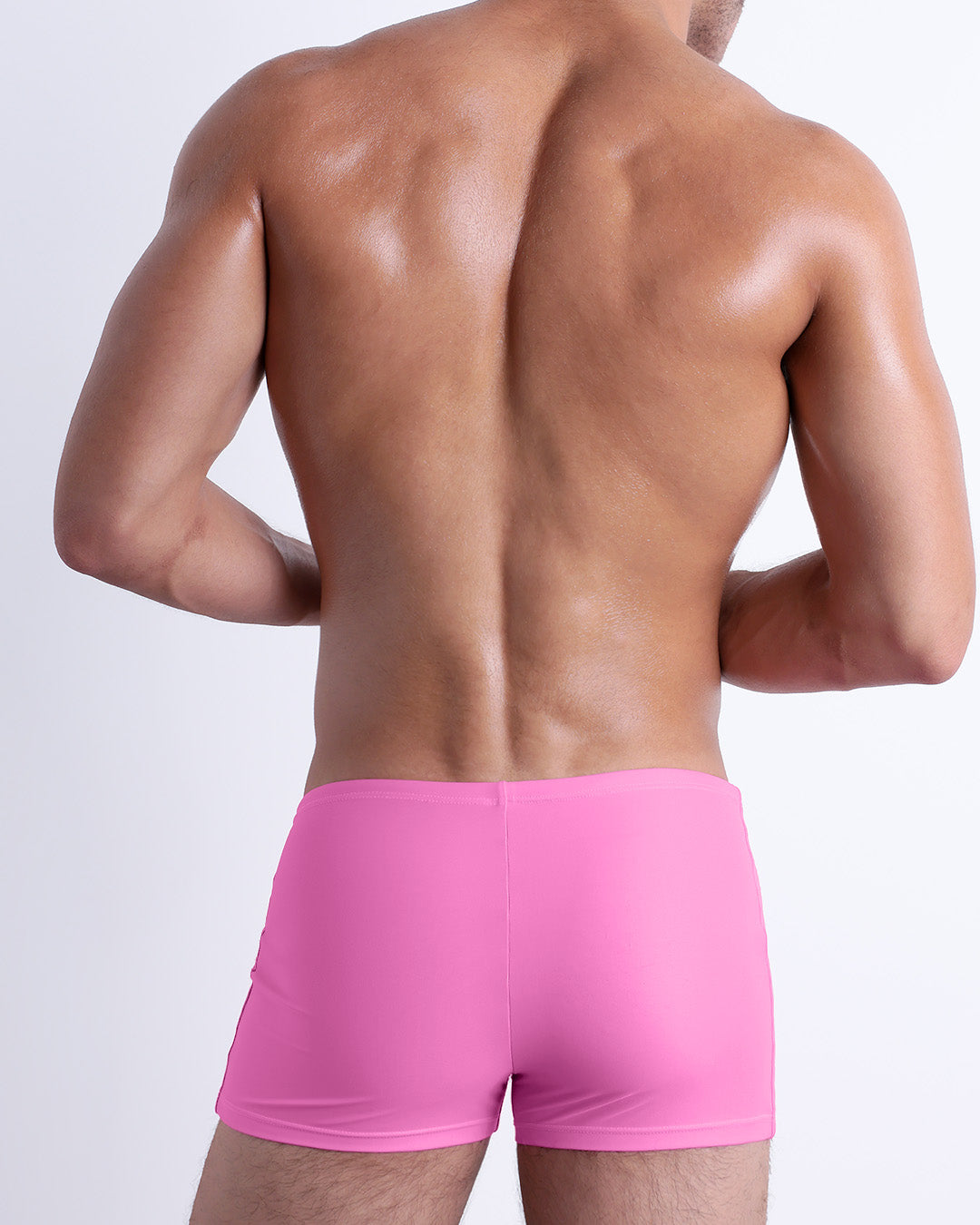 Back view of a male model wearing the PINKTYQUE men’s swim trunks by DC2 Miami in a solid vibrant pink color.