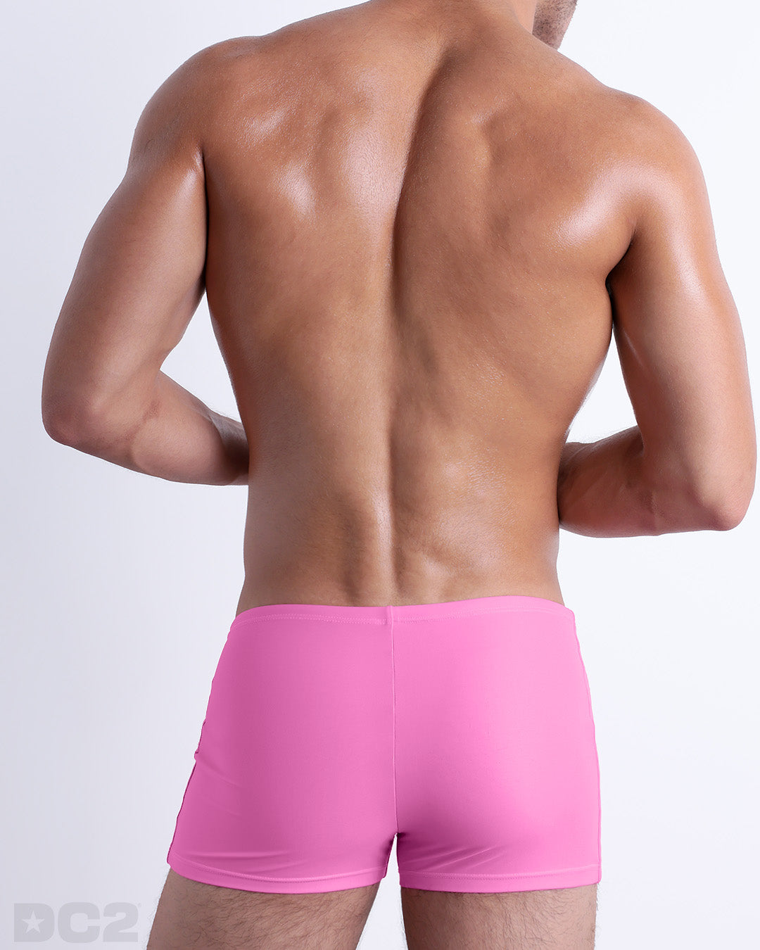 Back view of a male model wearing the PINKTYQUE men’s swim trunks by BANG! Miami in a solid vibrant pink color.
