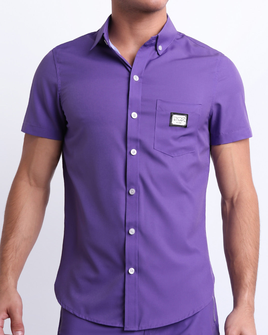 This is a front view of a male model looking sexy in a PURPLE MACHINE stretch shirt for men. The shirt is a vibrant violet color on the left pocket. It's a premium quality button-up top made by DC2, a Miami-based men's beachwear brand.