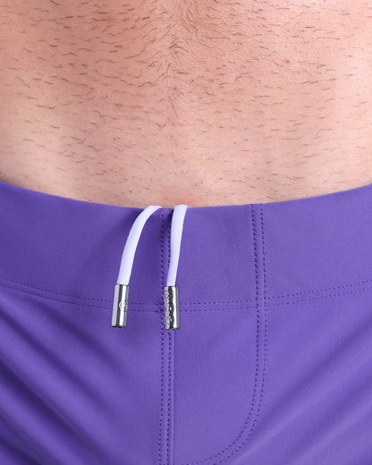 Close-up view of men’s summer beach shorts by DC2 clothing brand, showing white cord with custom branded metallic silver cord ends.