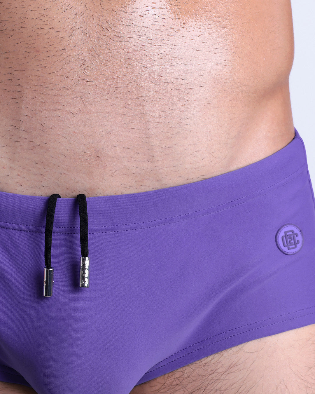 Close-up view of the PURPLE MACHINE men’s drawstring briefs showing black cord with custom branded metallic silver cord ends, and matching custom eyelet trims in silver.