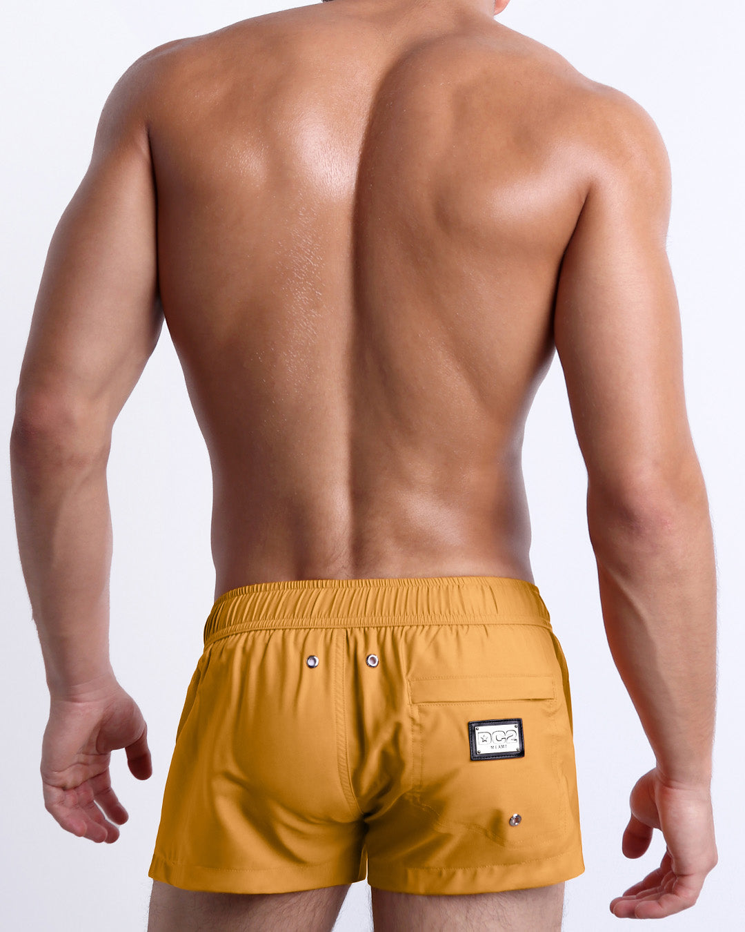 Back view of the RETRO MUSTARD beach Mini Shorts in a solid yellow mustard color, complete with a back zippered pocket, designed by DC2 a capsule brand by BANG! Clothes based in Miami.