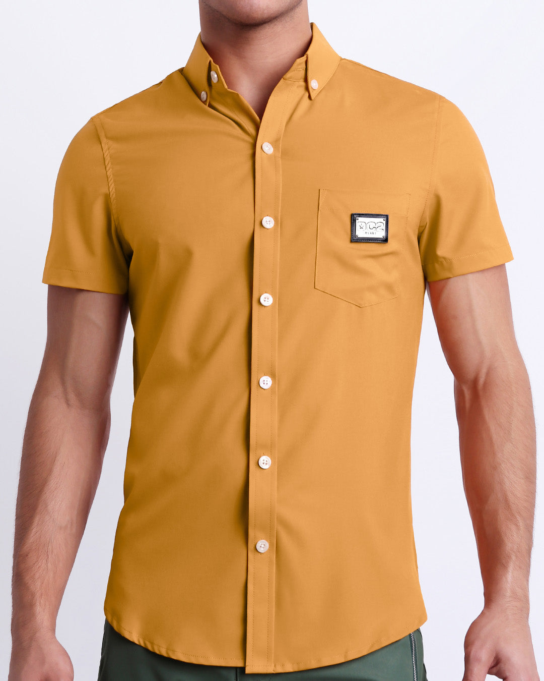 This is a front view of a male model looking sexy in a RETRO MUSTARD stretch shirt for men. The shirt is a solid mustard yellow color on the left pocket. It's a premium quality button-up top made by DC2, a Miami-based men's beachwear brand.