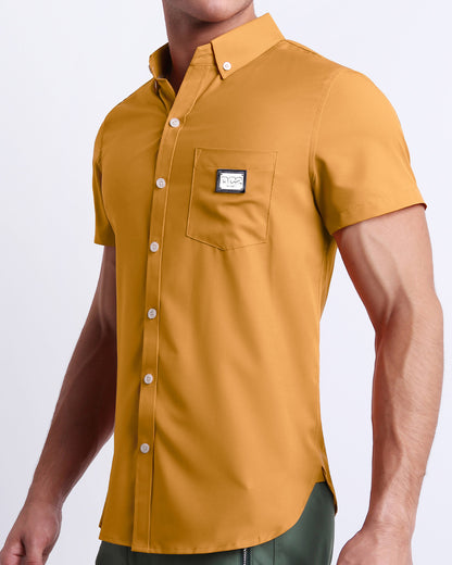 Side view of a masculine model wearing the men’s RETRO MUSTARD Summer button-down shirt in a solid dark yellow color. This high-quality shirt is by DC2, a men’s beachwear brand from Miami.