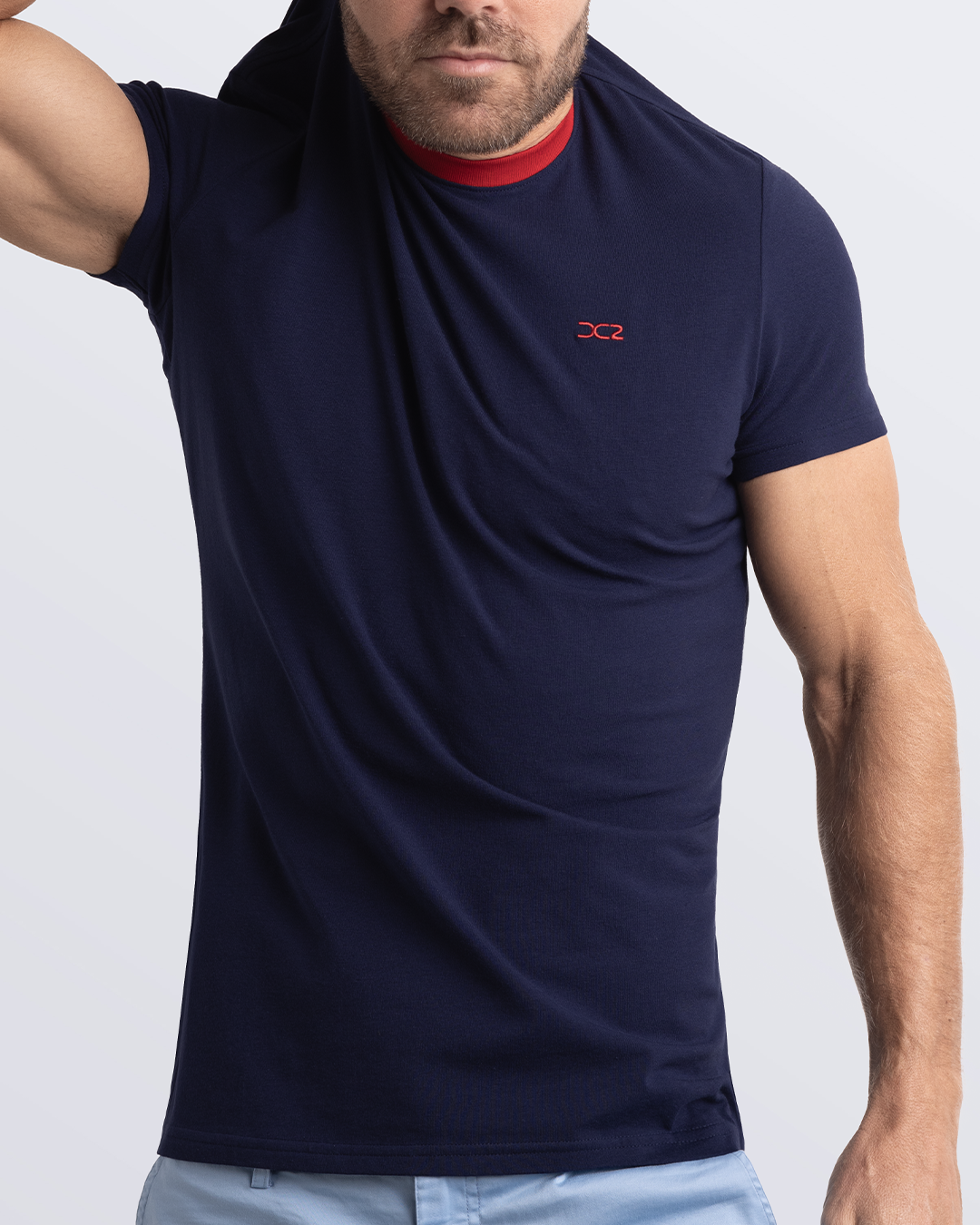 A model adjusting a navy blue Pima cotton t-shirt with a bold red collar, showcasing the breathable, lightweight fabric ideal for summer beachwear and street style. Part of the DC2 Miami men's casual collection, featuring a perfect fit for active wear