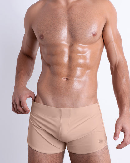 Front view of a model wearing the SKINNY DIP men’s swimming bottoms in a solid nude color by DC2, a men's beachwear brand from Miami.