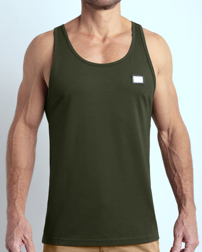 Frontal view of male model wearing the SLICK GREEN in a solid dark green color casual gym tank top for men by the DC2 brand of men's beachwear from Miami.