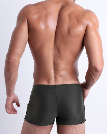 Back view of a male model wearing the SLIM GREEN men’s swim trunks by DC2 Miami in a solid pine green color.