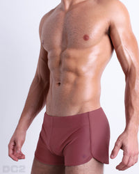 Side view of men’s Summer vintage 80s sprint shorts in SUN-KISSED RED a solid light brick red color made by Miami based Bang capsule brand, DC2.