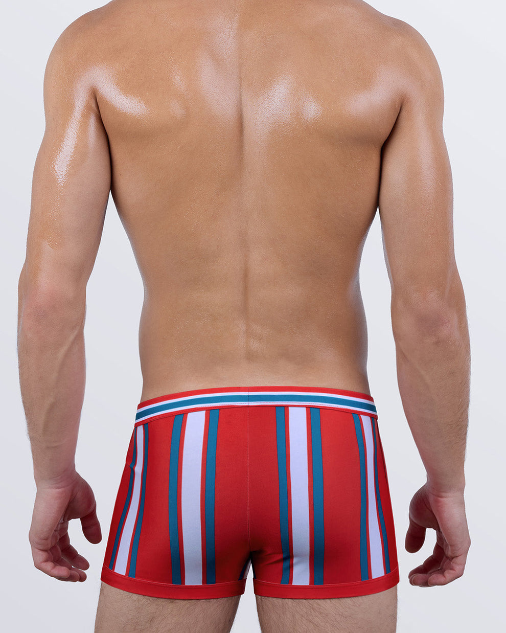 Back view of SWIFT STRIPES swim trunks showcasing full coverage and a sleek, athletic design in red with teal and white stripes. Form-fitting and supportive for all-day wear.
