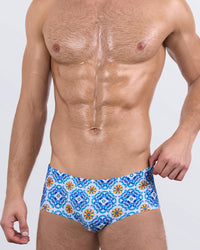 Men's designer swim sunga – THE TILE IS HIGH by DC2 Miami, featuring Italian ceramic tile-inspired print in blue, orange, and white on square-cut swimsuit for men.