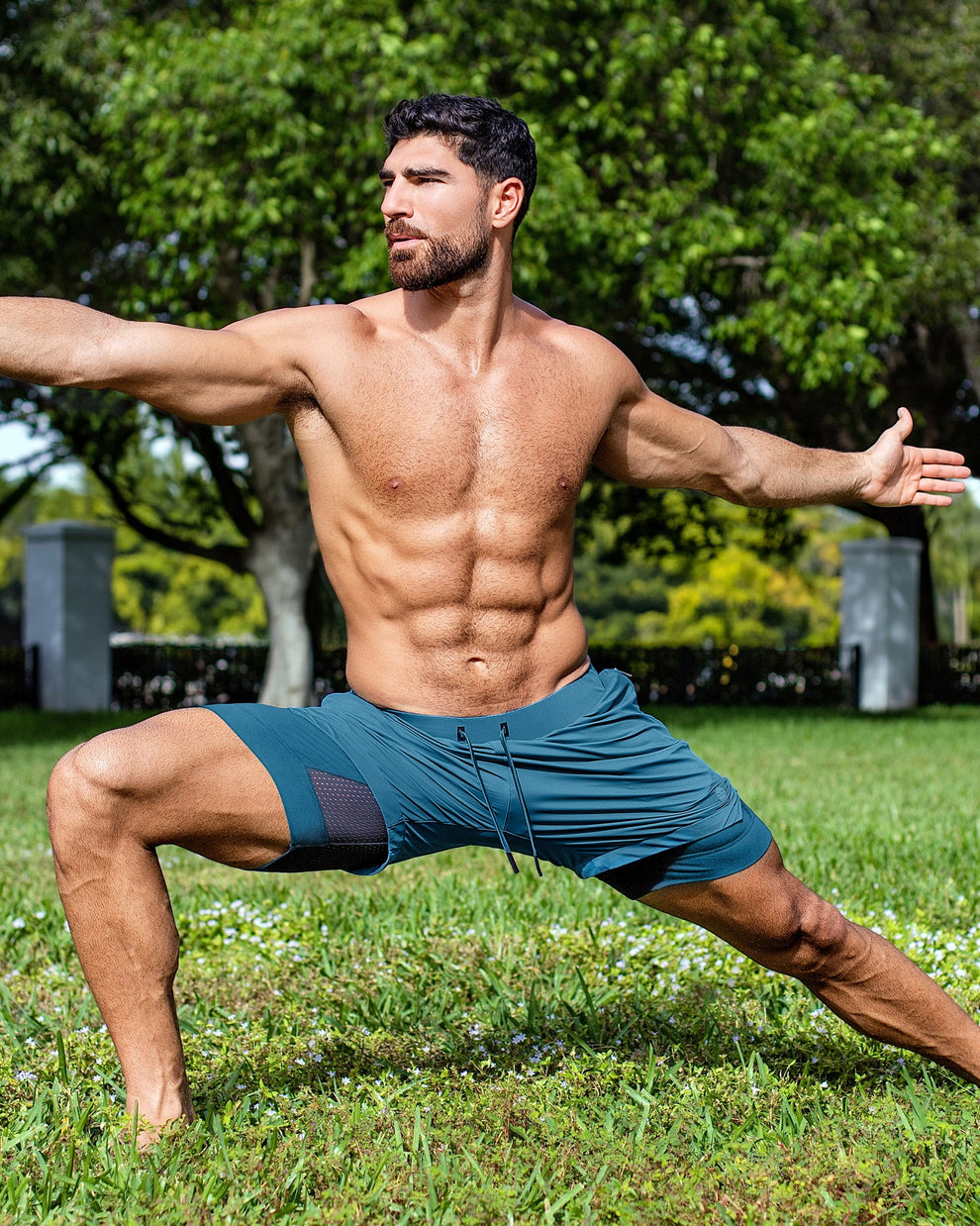 DC2 Miami Teal Endurance 2-in-1 Gym Shorts — model wearing teal men’s training shorts in an outdoor yoga pose.