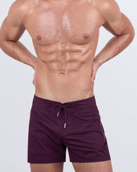A male model wearing the VERY BERRY - Flex Shorts by DC2 Miami. These stylish shorts come in a rich berry hue, featuring a lace-up front and water-resistant metallic zippers.