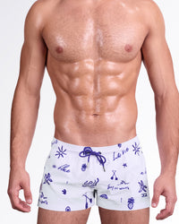DC2 Viva La Vida (Blue) Poolside Shorts — model wearing white poolside swim shorts featuring playful blue hand-drawn beach icons and text, adjustable drawstring waistband, and a modern short-length beach fit.