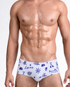 DC2 Viva La Vida (Blue) — model wearing Viva La Vida Blue Swim Sunga featuring a crisp white base with bold cobalt blue illustrated icons and script details in a sleek, body-contouring silhouette.