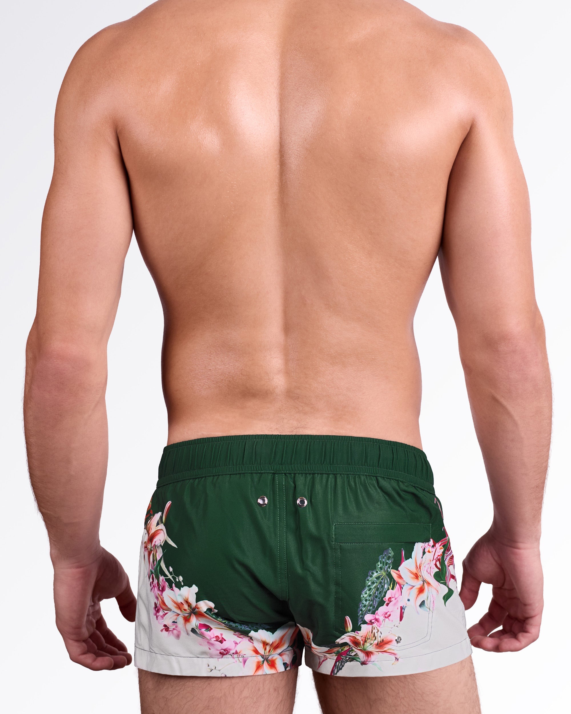 BANG! Bloom Service Swim Mini Shorts — back view highlighting solid green base with wraparound floral detailing and back pocket with metal eyelets.
