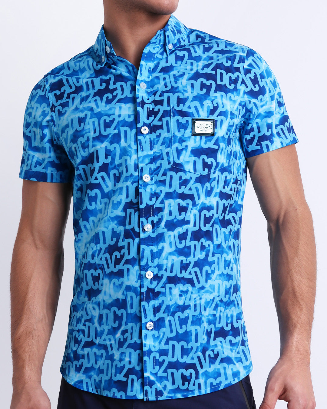 Male model wearing WET men’s sleeveless stretch shirt with stylish DC2 logo monogram motif in blue for men. This high-quality top by DC2, a men’s beachwear brand from Miami. 