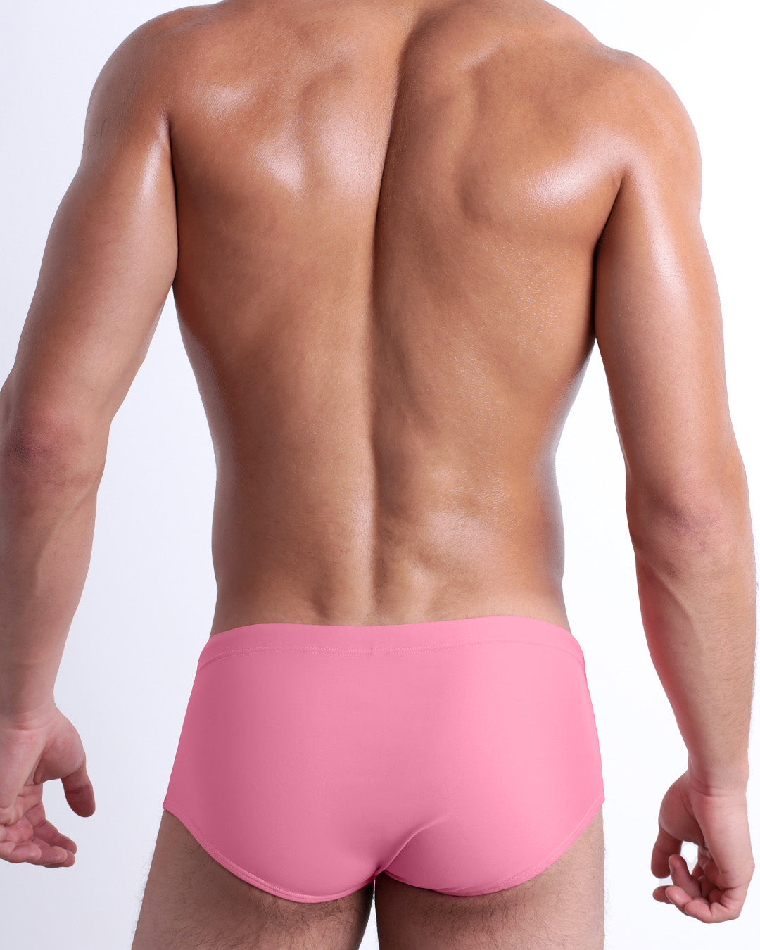 Back view of a male model wearing the WHISPERING ROSE beach Brazilian Sunga swimwear for men by DC2 Miami in a solid light pink color.