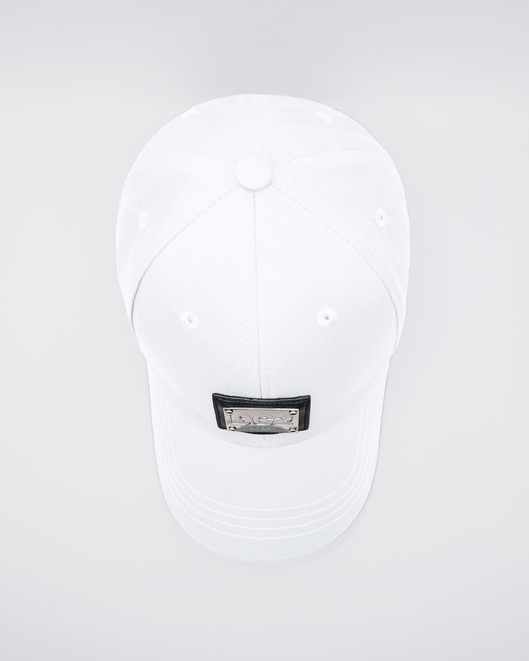 Close-up of a WHITE Baseball Cap with polished DC2 metallic silver plaque. Features ventilation eyelets on the cap to provide extra breathability, perfect for active wear.